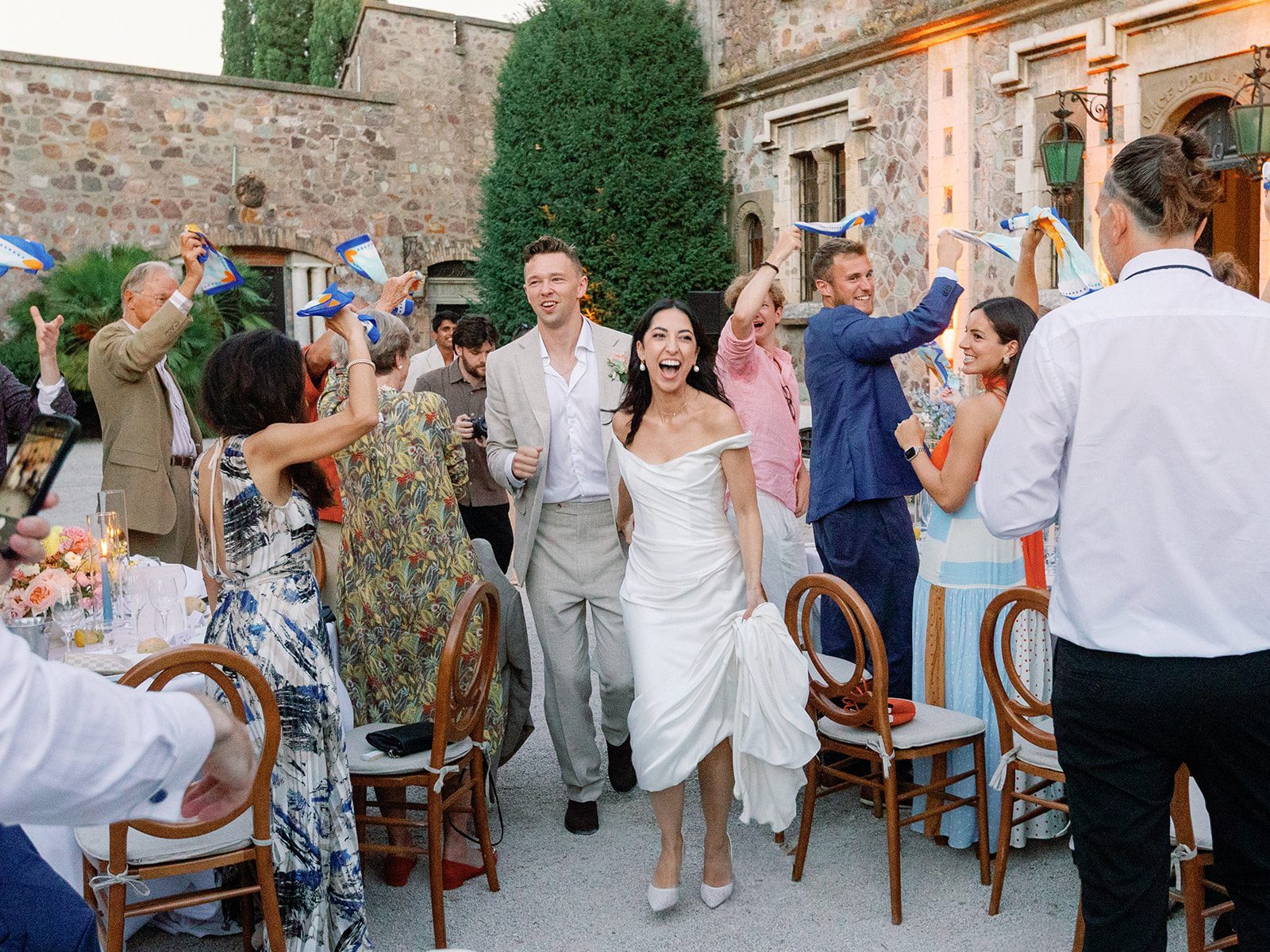 Reem and Toby walking through their guests as everyone waves their scarves